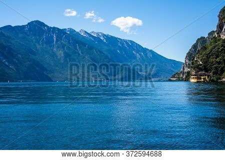 Beautiful View Of Lake Garda From The Ponale Road, With The Blue Sky, Sailing Boats, And The Green O