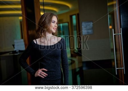 Stylish Girl Doing A Photo Shoot In A Beauty Salon. The Blonde Girl Is Photographed In A Black Dress