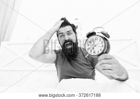 Totally Overslept. Get Up Right Now. Stressed Man Alarm Clock. Sleepy Man Holding Alarm Clock In Bed