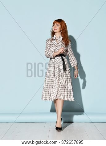 Young Beautiful Smiling Relaxed Red-haired Woman In Elegant Light Dress And Black High Heel Shoes Is