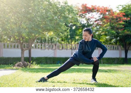 Portrait Of Asian Woman Workout Before Running At Village Park. Cheerful Runner Stretching And Warmi