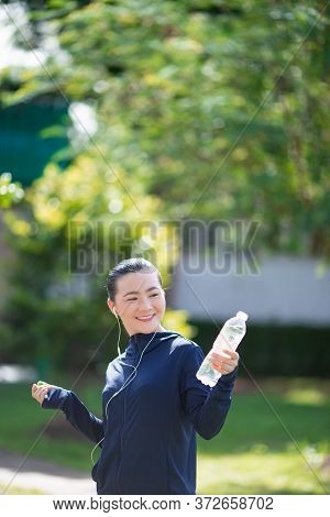 Portrait Of Asian Woman Wearing Earphones Listening To Music Was Sick With Fever At Park. Woman Exer