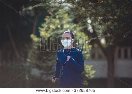 Portrait Of Asian Woman Wearing Earphones Listening To Music Was Sick With Fever At Park. Woman Exer