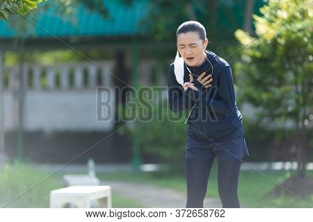 Portrait Of Asian Woman Wearing Earphones Listening To Music Was Sick With Fever At Park. Woman Exer