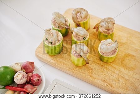 Wooden Board With Zuccini Pieces Filled With Ground Meat Decorated With Shrimps