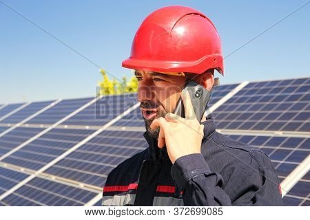 Tehnician In A Red Helmet Makes A Phone Call In The Solar Power Plant