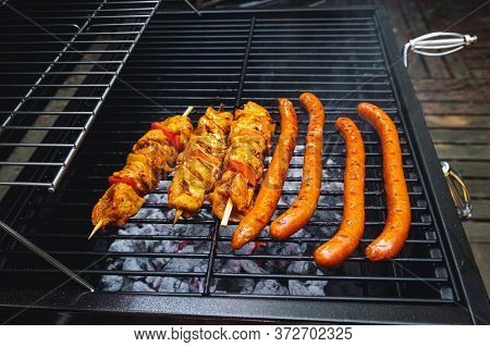 Meat Skewers And Sausages Being Grilled On A Barbecue, Pork Chipolata.
