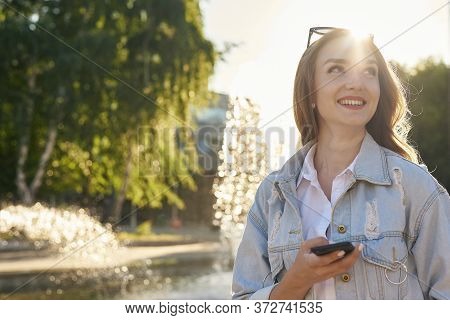 The Glad Girl With Phone. The Girl Gets A Plessure Message. The Attractive Girl Is In Sunlight