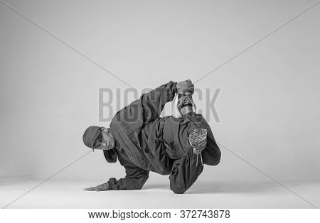 A Man Hip Hop Dancer Or Bboy Freezes In One Pose On A White Background. Bboy Doing Stylish Stunts.