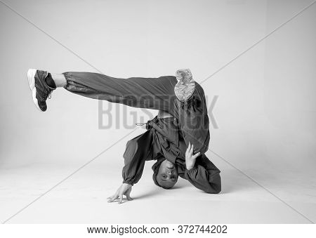 A Man Hip Hop Dancer Or Bboy Freezes In One Pose On A White Background. Bboy Doing Stylish Stunts.
