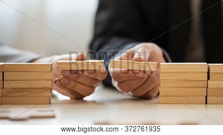Closeup View Of Businessman And Businesswoman Making A Bridge Of Wooden Blocks Between Two Stacks Of