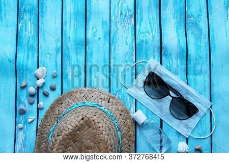 Straw Hat, Sunglasses, Pebbles, Medical Mask And Antiseptic On A Wooden Background. The Tourist Cris