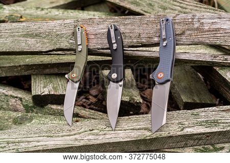 Several Folding Knives On A Wooden Fence. Pocket Knives On A Fence.
