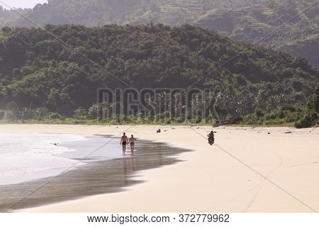 Couple Holding Hands And Scooter At Mawun Beach Lombok. Kuta Lombok Is An Exotic Paradise On The Ind