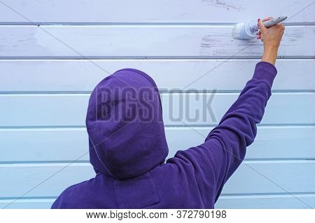 A Woman Using A Brush To Paint A Wall Blue