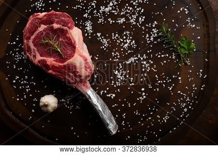 Top View Raw Tomahawk Beef Steak With Ingredients For Grilling With A Spice Rub, Fresh Rosemary And 