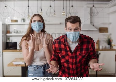 Irritated Couple In Medical Masks Screaming And Gesturing While Looking At
