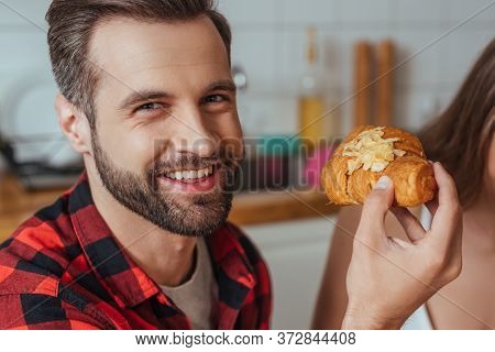 View Of Girl Near Happy Man Holding Croissant And Looking At Camera