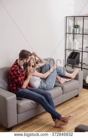 Man Calming Depressed Girlfriend While Sitting On Sofa At Home