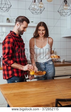 Young Couple Holding Plates With Delicious Croissants And Glass Of Orange Juice