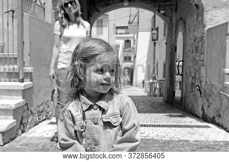 Portrait Of Pretty Little Girl In The Italian Village. Her Mum On The Background. San Felice Circeo,