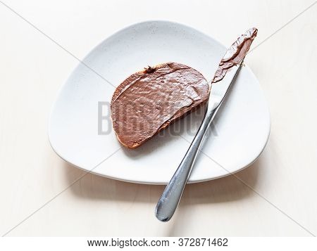 Above View Of Toast With Chocolatte And Hazelnut Spread And Knife On Plate On Table