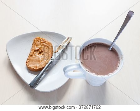 Top View Of Mug With Hot Chocolatte And Toast With Peanut Butter On Plate On Table