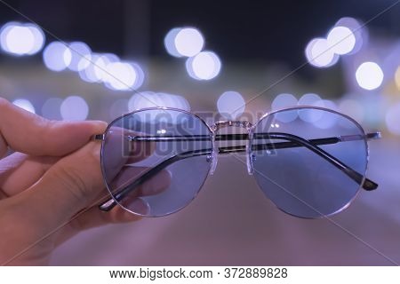 Black Glasses Have A Male Hand With A Vintage Bokeh Background.