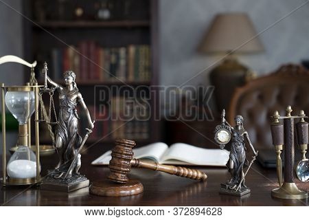 Law Theme. Judge Chamber. Gavel And Themis Statue On Brown Shining Desk. Collection Of Legal Books I