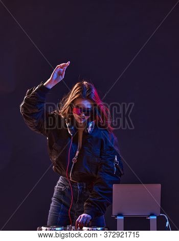 Stylish Dj Girl With Headphones And Glasses On The Bomber Jacket Mixes The Music At The Party And Ne