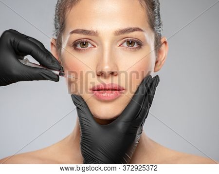 Young caucasian woman getting  cosmetic injection near the eyes. Beautiful woman gets  injection in her face. Adult girl gets cosmetic injection of  in a clinic. Beauty treatments