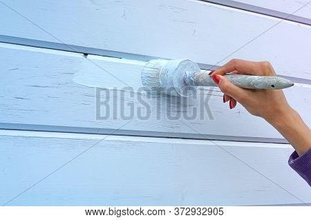 A Woman Using A Brush To Paint A Wall Blue