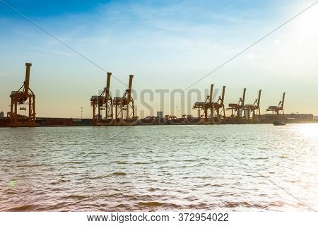 A Shipping Crane Of Maritime Transportation Beside River Under Sunshine Day