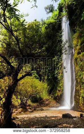 Waterfall Landscape View Of Fresh Water Flows Over A Vertical Drop To Green Field In Tropicana