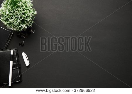 Top view of modern black office desk with calc, notebook, pen and a lot of things. Flat lay table layout. Copy space for text.