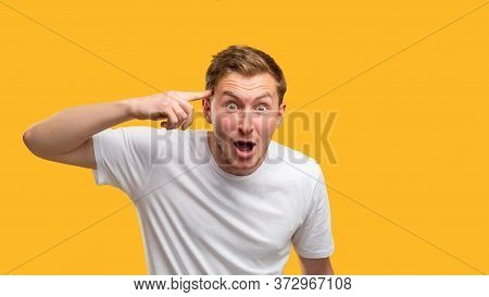 Insane Gesture. Mind Blowing. Shocked Man With Finger On Temple Isolated On Orange Background.