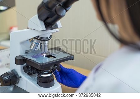 Laboratory Assistant Is Looking Through A Microscope. Close-up Doctor Laboratory Assistant Looking T