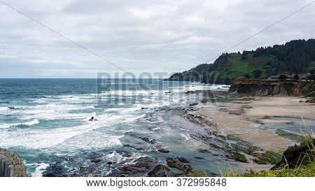 Landscape Of An Oregon Beach Between Coss Bay And Charleston, Featuring Rocks And A Cloudy Sky