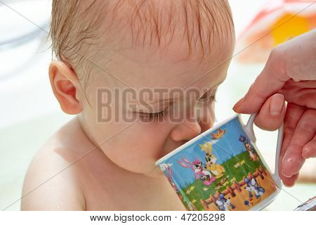 Moeder geeft om te drinken uit een beker baby