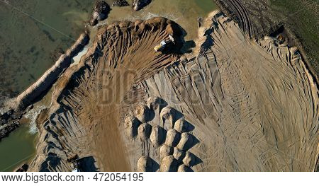 Arial View Of Open Pit Sand Mine. A Front Loader Loads Sand From Piles. Heavy Mining Machinery Worki