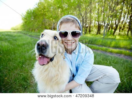 Retrato do rapaz bonito em óculos de sol e seu amigo peludo ao ar livre