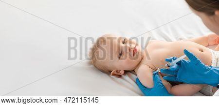 Doctor Vaccinating Smiling Baby In Clinic. One Year Little Baby Get An Injection. Pediatrician And P