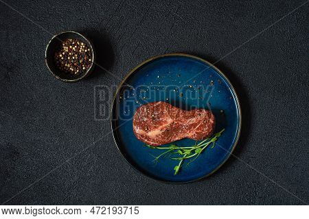 Raw Marbled Beef Steak On Plate Ready To Cook With Microgreens. The Shape Of The Steak Is Light Bulb