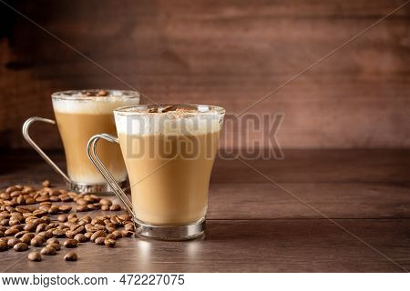 Two Cups Of Coffee Latte, With Milk Foam In Glass Cups. Coffee Beans And Wooden Background. Copy Spa