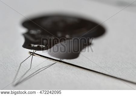 Sewing Needle Threader Tool In Use And A Single Black String.