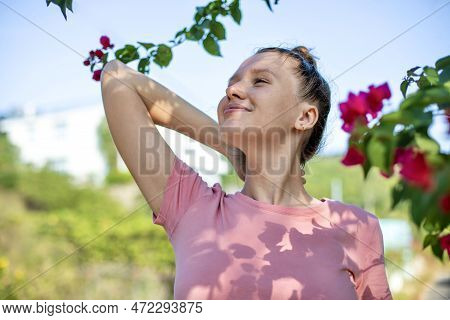 Portrait Of Happy Beautiful Girl, Young Positive Woman Is Smelling Beautiful Yellow Flowers In The G