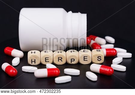 Medical Concept. On A Black Background Are Red-white Capsules, Tablets, A Jar And Cubes With The Ins
