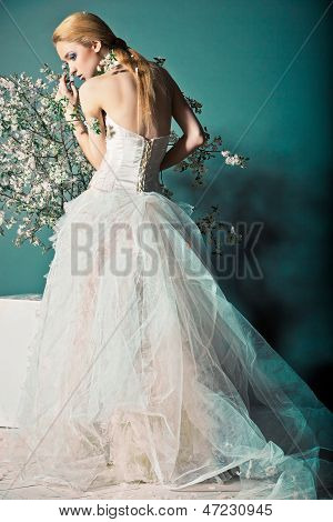 Bride in wedding dress behind bush with flowers