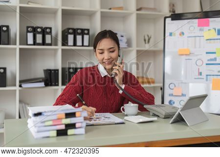 Beautiful Asian Woman Talking On Phone At Creative Office. Happy Smiling Businesswoman Answering Tel