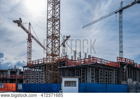 Industrial Landscape With Silhouettes Of Constraction Cranes On Dramatic Sky Background. New Develop